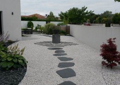 Pas japonais irréguliers menant la "fontaine totem"joliment mise en valeur par des barrettes de schiste