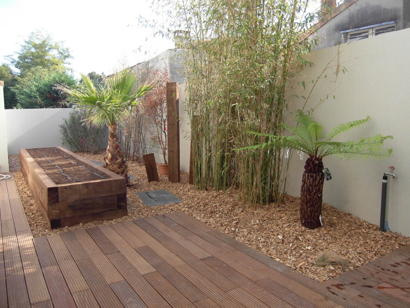 La terrasse est composée de lames d’ipé courtes, composition atypique sans entretien avec mulch en plaquettes de chêne La terrasse est composée de lames d'ipé courtes, composition atypique sans entretien avec mulch en plaquettes de chêne
