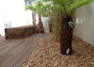 Jardin exotique avec jardinière en traverses de pin et terrasse en lames d'ipé rainurées