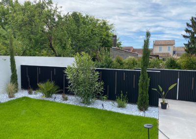 Au fond les barrières sur-mesure en métal qui créent un chemin menant au potager